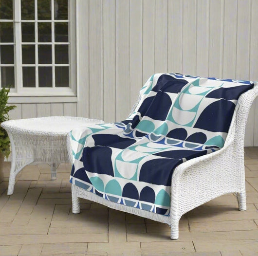 a beautiful abstract turquoise blue and grey blanket on a white outdoor chair