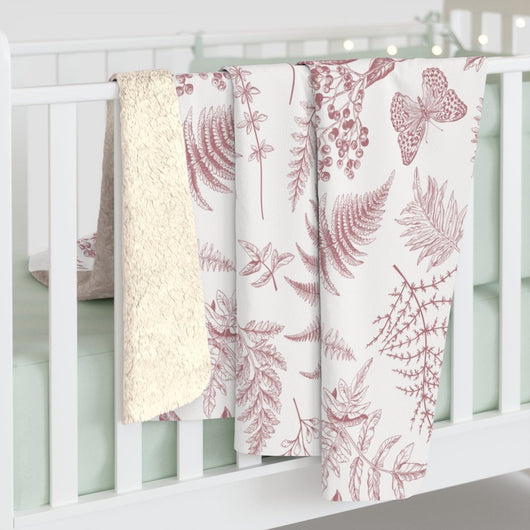 Baby blanket with pink ferns on side of crib