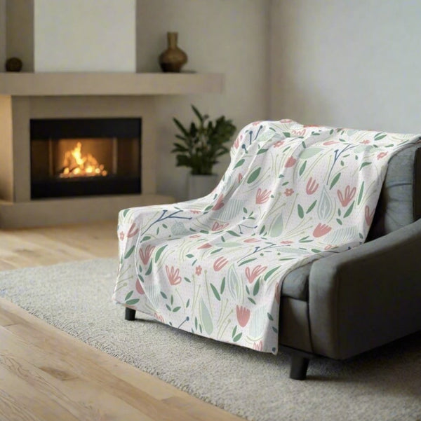 pink and green throw blanket on chair in front of fire