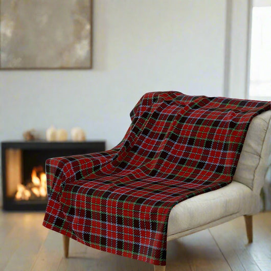 Red plaid throw blanket on a white chair in front of a fire