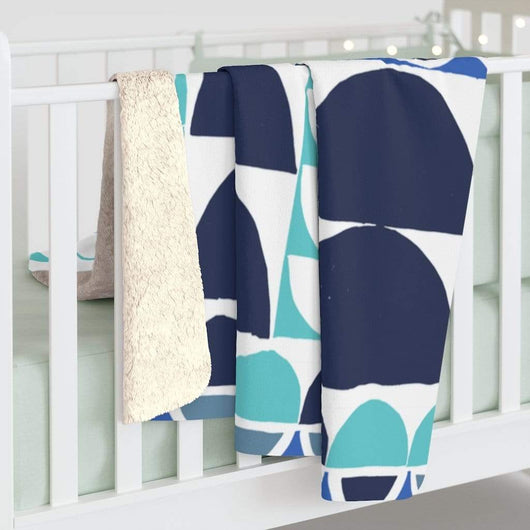 Turquoise and Blue Sherpa Fleece Blanket hanging on a crib